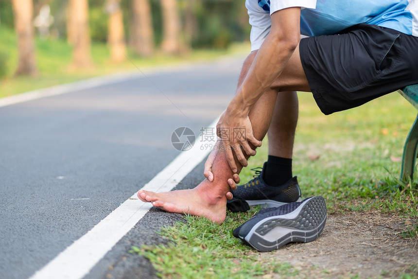 男人在训练亚裔运动员在上午和健康概念外跑步和锻炼后脚踝疼痛和问题时手持运动腿部受伤肌肉痛苦的年轻健身男子在训练亚裔跑者帕努瓦马拉图片