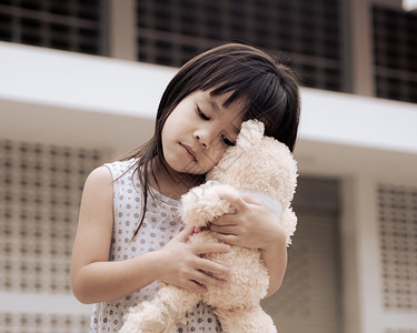 抱着她的泰迪熊可怜小女孩站在家庭后院留中以隔离冠状流行防止这种病畅快停留生活背景图片