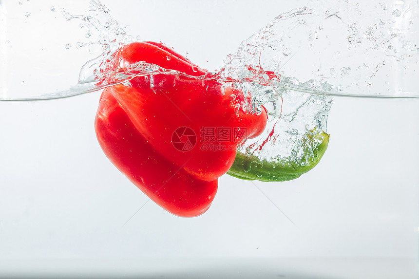 降低甜辣椒在水中喷洒红辣椒在白色背景的面上加红甜辣椒是一种不新鲜的生图片