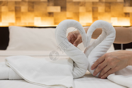 洗过汽车旅馆在床单上贴鲜白浴巾的折叠天鹅鸟紧双手放在旅馆床单上情人节图片