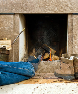 在一个小壁炉旁躲藏着暖热的乌吉和放松越过炉边一种伸出的高清图片素材