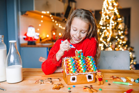 姜饼圣诞树可爱的小女孩装饰着姜饼屋有迷人的美丽厨房有灯光和圣诞树桌子上还有蜡烛圣诞快乐和节日小姑娘在厨房做圣诞姜饼屋在厨房饼干新的幸福背景