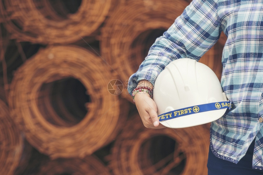 训练工厂家女建筑程师在地身戴安全白色钢帽的建筑工场薪女程师土木带有硬帽子安全头盔的女建筑工程师概念a妇女建筑工程师图片