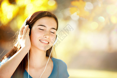 一种在秋天的优美节日用耳机聆听音乐节目以欢之情微笑闭眼年轻女孩睛季节图片