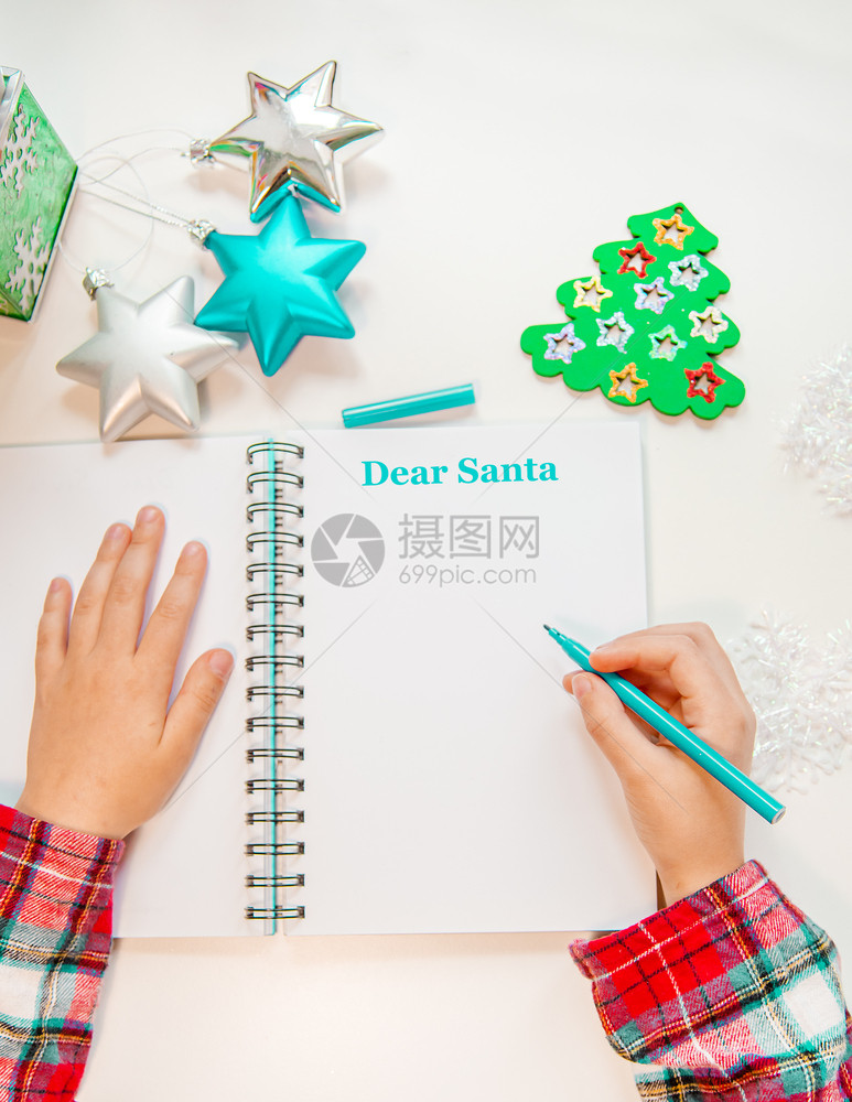 孩子们亲爱的圣诞老人信贺卡一个拿着笔的孩子在木制背景上的白纸写字带有新年装饰童梦想的礼物新年概念亲爱的圣诞老人信贺卡一个拿着笔的图片