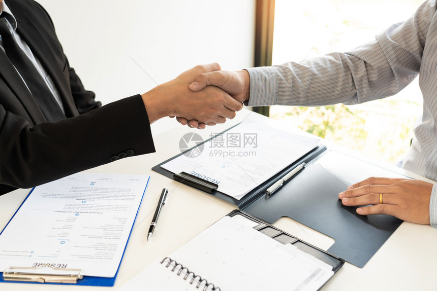 握手概念在完成交易项目或就办公室背景进行谈判时成功后保持手握或者以办公室背景为谈判的讨价还支持超过商人图片