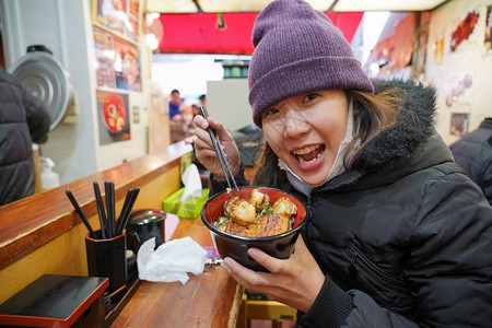 淡淡微笑汤唯亚洲年轻女享受日本菜美食在鱼市东京日本的碗里有大米和虾烤的保持美丽背景