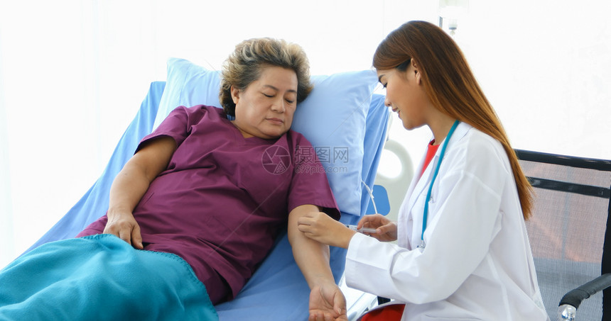 医生正在用注射器给躺在床上的生病老妇人注射疫苗图片