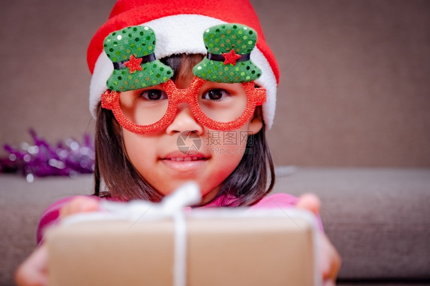 十二月盒子在室内快乐的小女孩戴着圣诞帽在家送礼物新年快乐圣诞图片