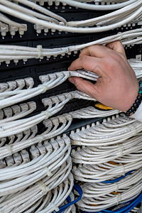 在职的白色男子在网络服务器室工作拥有数字通信和互联网络开关光纤枢纽的网络服务器机房金属丝中心高清图片素材