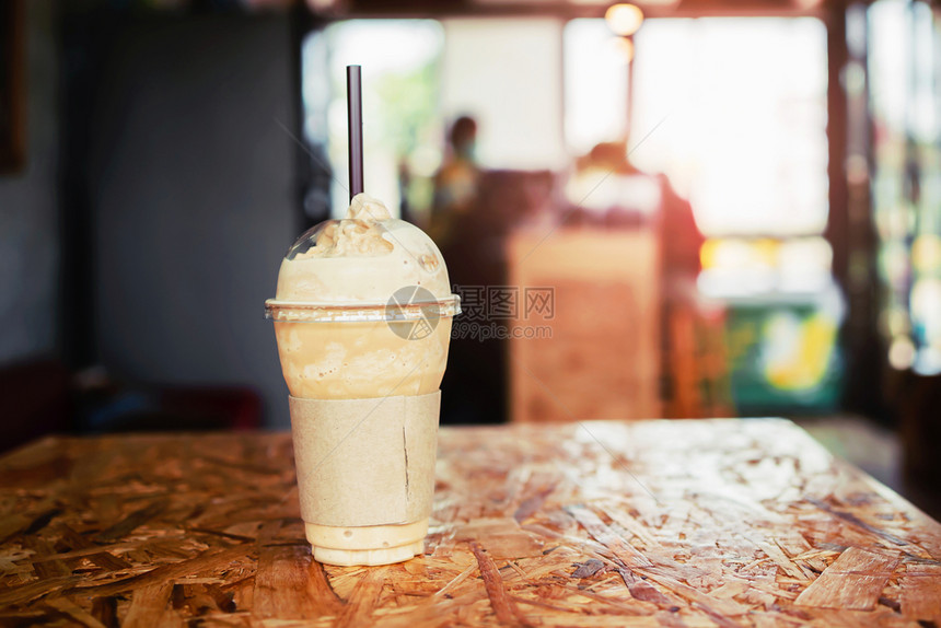 木制的冰放在商店桌上的塑料杯中咖啡棕色图片