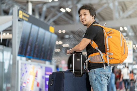 为了在现代机场飞行信息屏幕上登机旅行和具有技术概念的运输等现代机场旅行和运输时有护照的亚洲旅行者在飞板上站立着检查行李的肖像团体车站高清图片素材