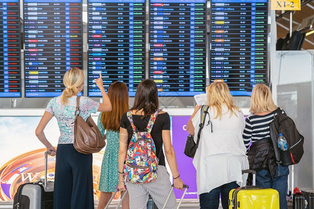 现代的木板在机场的飞行信息屏幕旅和带有技术概念的运输上登入飞行信息屏在机板上站着行李的旅客背靠边办理登机记手续提箱国际的高清图片素材