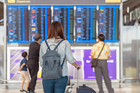 在现代机场旅行和运输概念的飞行信息屏幕上登入机检查时背着行李站在飞板上的亚洲女旅行者背面在飞信息屏幕上登机国际的游客木板手提箱高清图片素材