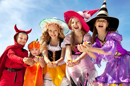 摄影焦糖五个快乐儿童在万圣节装饰中拿着糖果在蓝天的南瓜和魔鬼假期图片