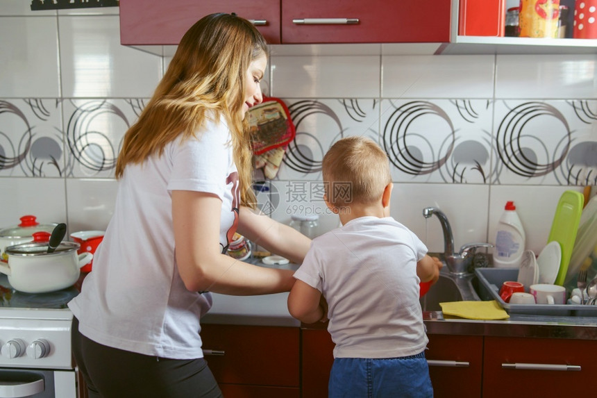 在家厨房的里看母亲和儿子背影年轻caucasiansian妇女及其小男孩花时间准备午餐在白天做母亲和儿童成长的概念中腰部起内的后图片