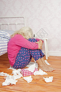 坐着悲伤躺在床边的地板上有粉色睡衣和纸巾的可怜女人困扰图片