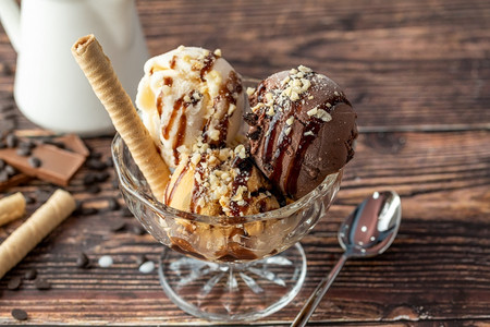 服务杯子盘巧克力奶油和焦糖罗马人冰淇淋在玻璃碗里加了栗子和巧克力酱背景图片