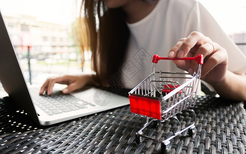 年轻快乐的亚洲女在笔记本电脑上网购物随意的银行业坐着图片
