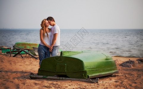 蓝色的美丽夫妻在海滩上拥抱脸抚摸图片