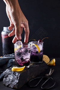 喝立方体甜的新鲜蓝莓鸡尾酒加柠檬皮和樱桃背景图片