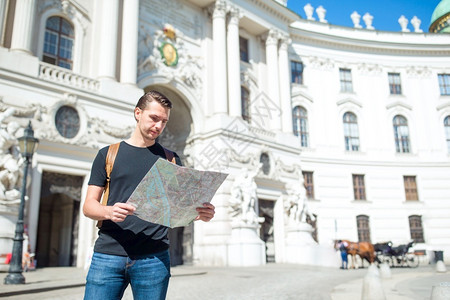 旅游拿着城市的男游客在维也纳街头白人男孩在背景中看维也纳城市男文化图片