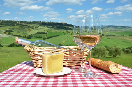 村庄乡的白葡萄酒奶酪和面包在彩布上与意大利的托斯卡纳风景对抗瓶子图片