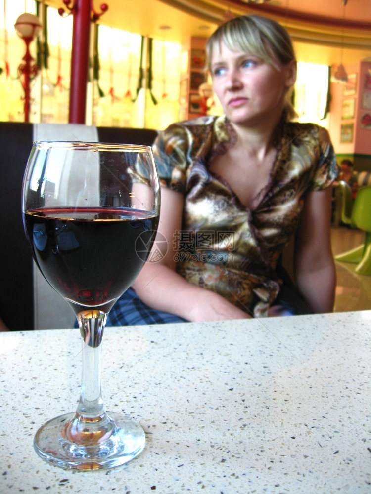 茶桌上的红酒杯和一位女孩在餐馆里拿着红酒杯的女孩晃动放松图片