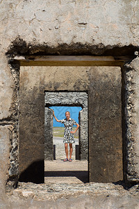 老的视窗白种女人正站在博内尔历史建筑的门前围墙图片