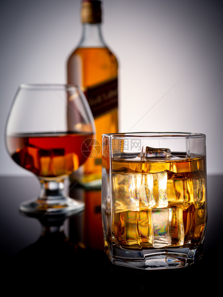 一杯加冰的威士忌在深色背景中一杯加威士忌和瓶好的生活经典图片