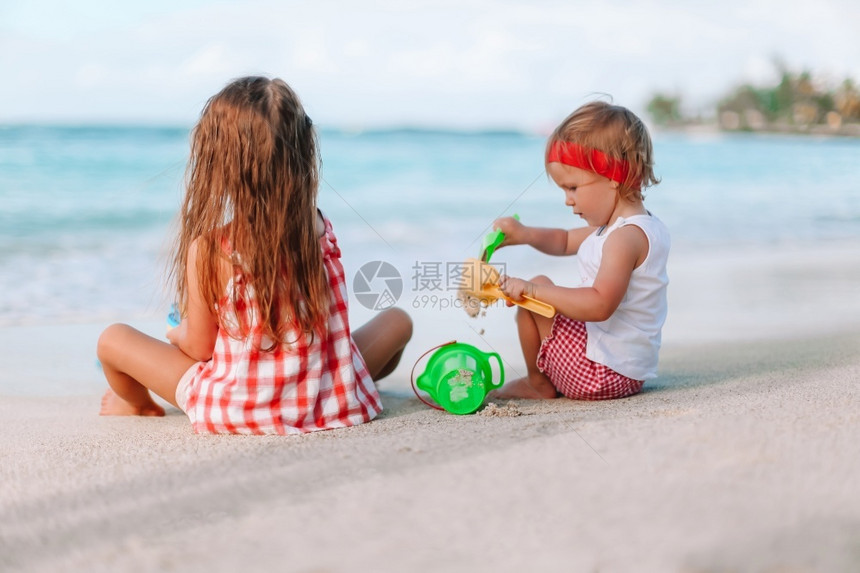 两个小女孩在白色热带海滩上做沙堡图片