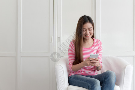 互联网移动的坐在家中客厅沙发上亚洲女在手机聊天时笑着快乐的容校对Portnoyinform人们电话高清图片素材