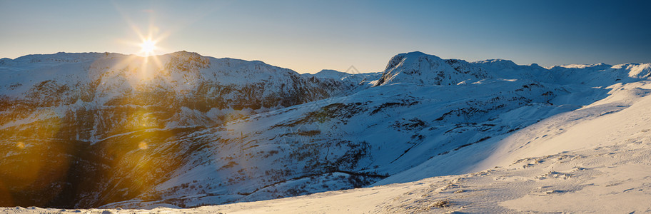 雪堆欧洲挪威积覆盖的山脉上太阳落日全景图片