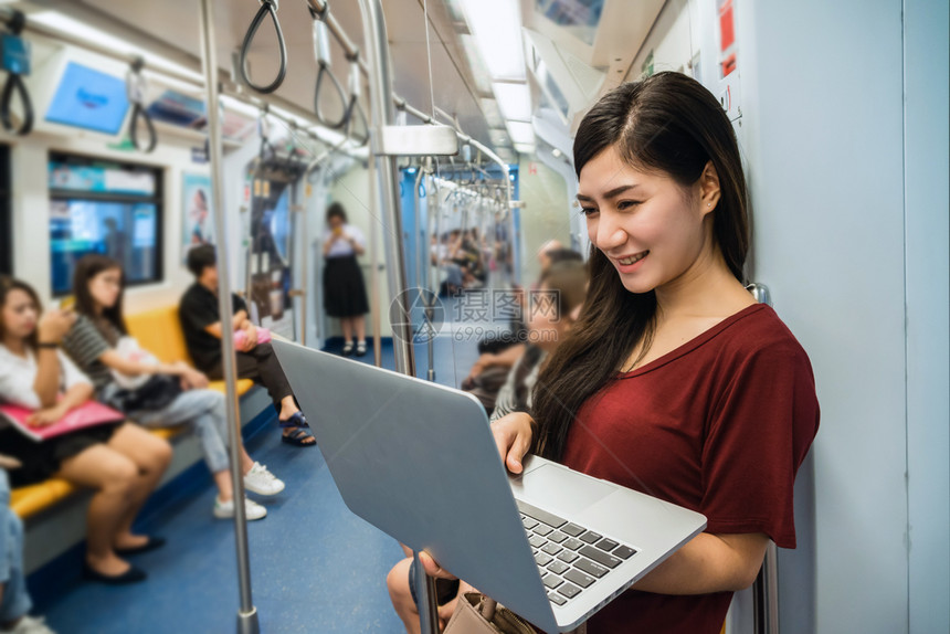 亚洲人随意的使用BTSSkytrain铁路或MRT地技术笔记本电脑在大城市旅行生活方式和运输概念上临时穿便衣的亚洲女旅客导轨图片