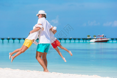 一种父母喜悦亲和孩子们一起在海滩上享受日落家庭假期快乐美丽的家庭在热带海滩度假快乐的高清图片素材