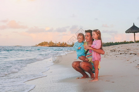团结父亲和孩子们一起在海滩上享受日落家庭假期快乐美丽的家庭在热带海滩度假绿松石阳光高清图片素材