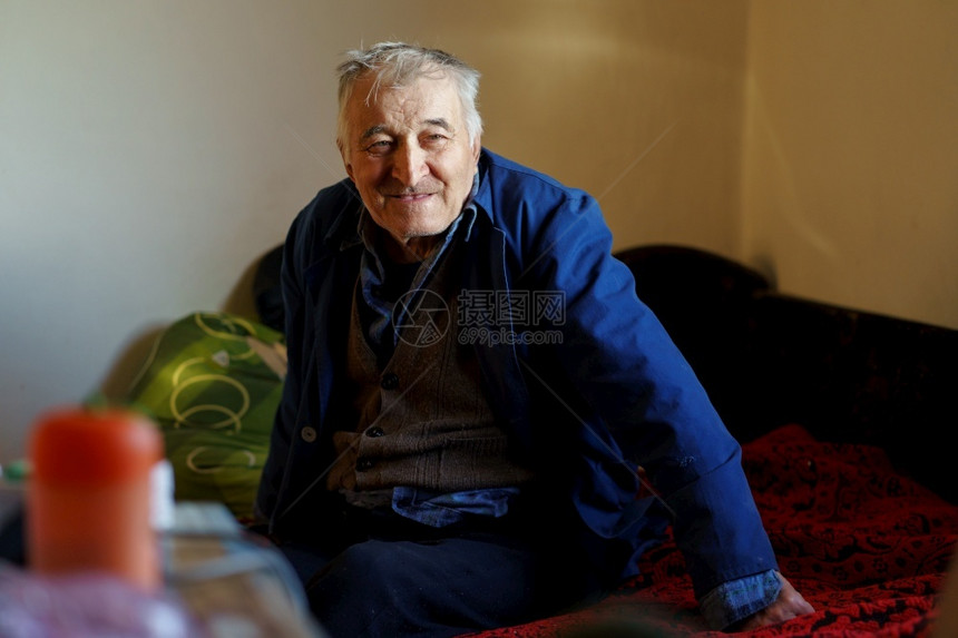 一名老年退休养恤金领取者坐在床上疗养院的一间房里独自坐在一个房间里白头发男看着一边笑坐健康陈年图片