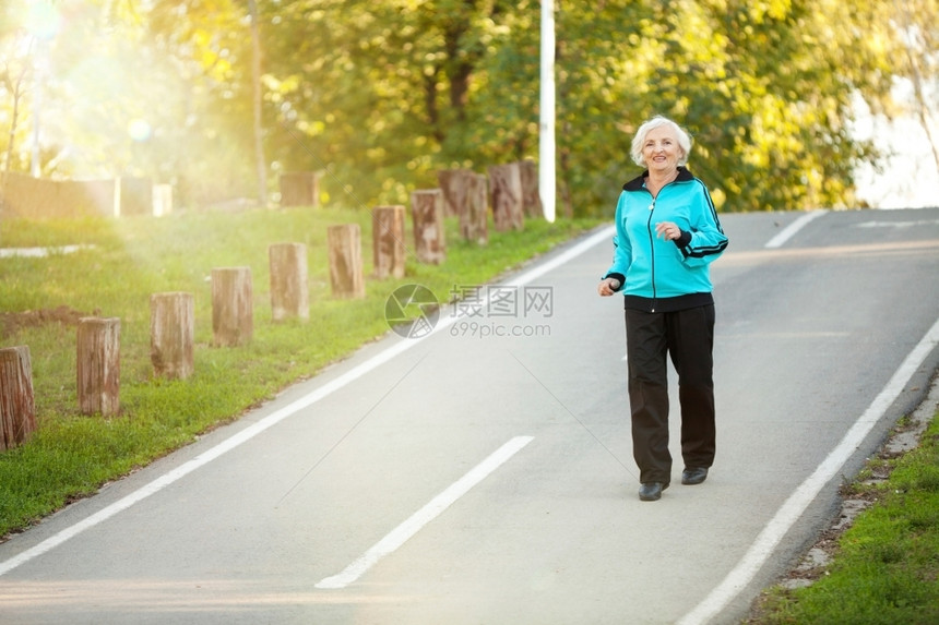 70岁的老年妇女在明秋晚的Pedestrian漫步道上慢跑晚幸福运动服图片