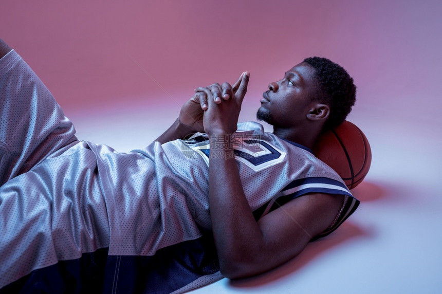 力量篮球运动员与躺在工作室尼龙背景在运动服装比赛中的男职业球手高身运动员篮球与躺在工作室中玩oopicapi图片