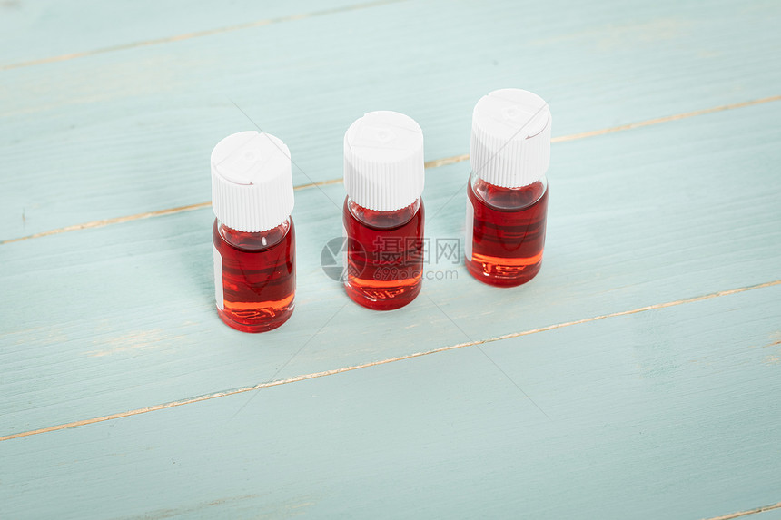 疾病抗生素糖尿三个装满红色液体的药瓶用绿木制成一排地列在绿色木制上图片
