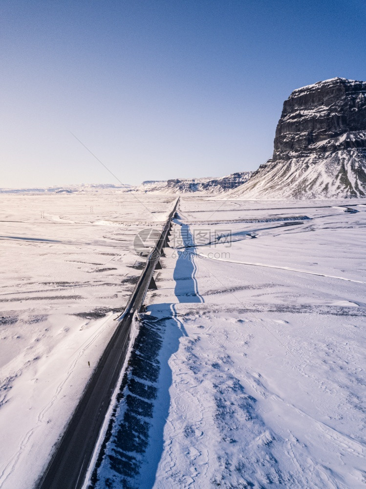 太阳蓝色的斯堪纳维亚语环形路1号在冰地的空中景象后面是洛马格努普山图片