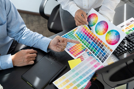 图形设计师或创造合作使用图形平板和与同事在办公桌上的图案来涂色在职的桌子背景图片