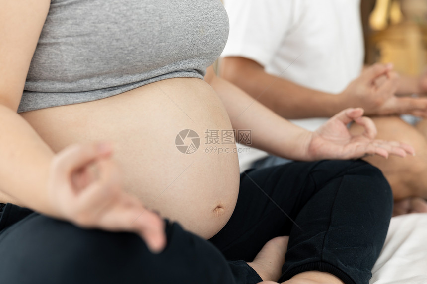 坐着怀孕的丈夫和妻子在白色卧室的上活瑜伽婴儿健康爱护概念有选择地关注女心图片