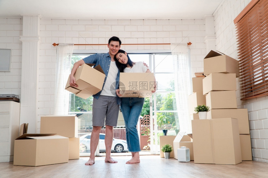 包装幸福的年轻夫妇携带纸板盒站在新房子前门移动日的新房门口搬家概念租房和屋主搬家明亮的男人图片