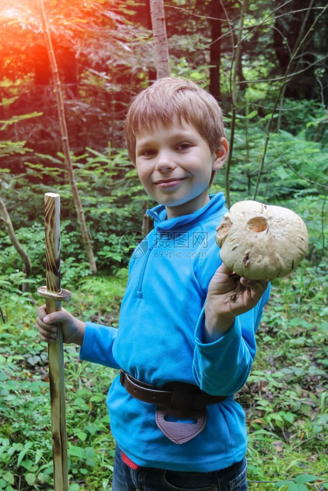 鞘在森林里微笑的男孩手里拿着大蘑菇阳光蓝色的图片