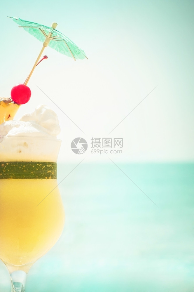 在热带海洋滩上配有水果和伞装饰的Pinacolada鸡尾酒及水果和伞状装饰的热带海边滨潮人岸天空图片