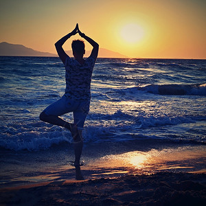 经过宁静红色的妇女冥想日落时在海滩的边放松瑜伽健康和SPA的概念自然高清图片素材