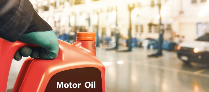 抓住加油机械师持有一加红色发动机油用于修理车间的汽发动机维修保养距离图片