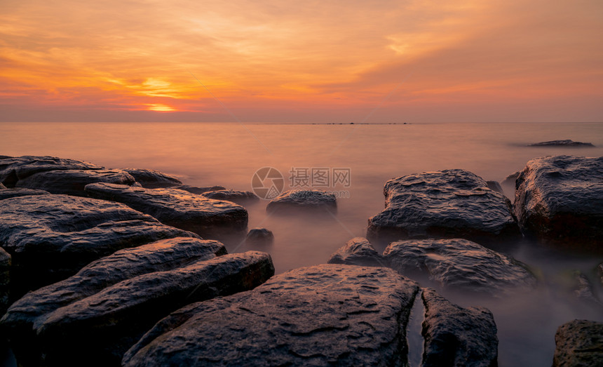 平静的宁日落时在石滩上的岩美丽海边夕阳天紫光海与空黄昏时的热带海风云天空和日落抽象背景平静放松生命景观假期图片