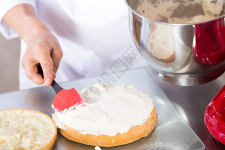 女士机器厨师装饰一个美味的蛋糕加奶油制服图片